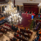 Vista panorámica del Paraninfo de La Nau durante el Solemne Acto de Apertura del Curso Académico de la Universitat de València, con autoridades en la mesa presidencial y académicos vestidos con birretes y togas de colores en los asientos.